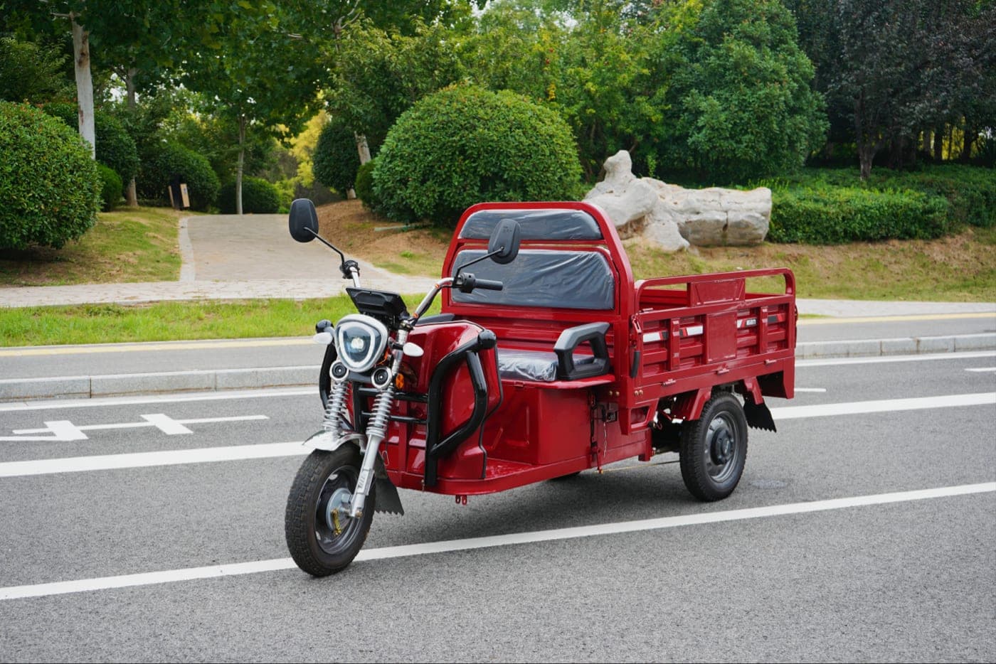 Red electric cargo tricycle with open steel bed for commercial hauling
